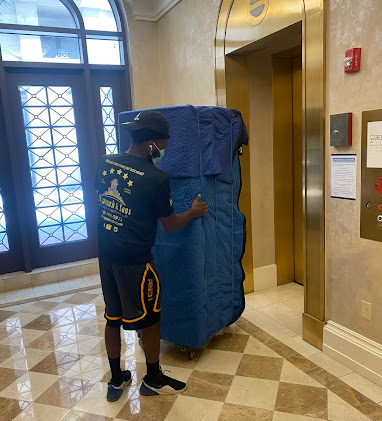 professional mover carrying safely wrapped furniture in new office